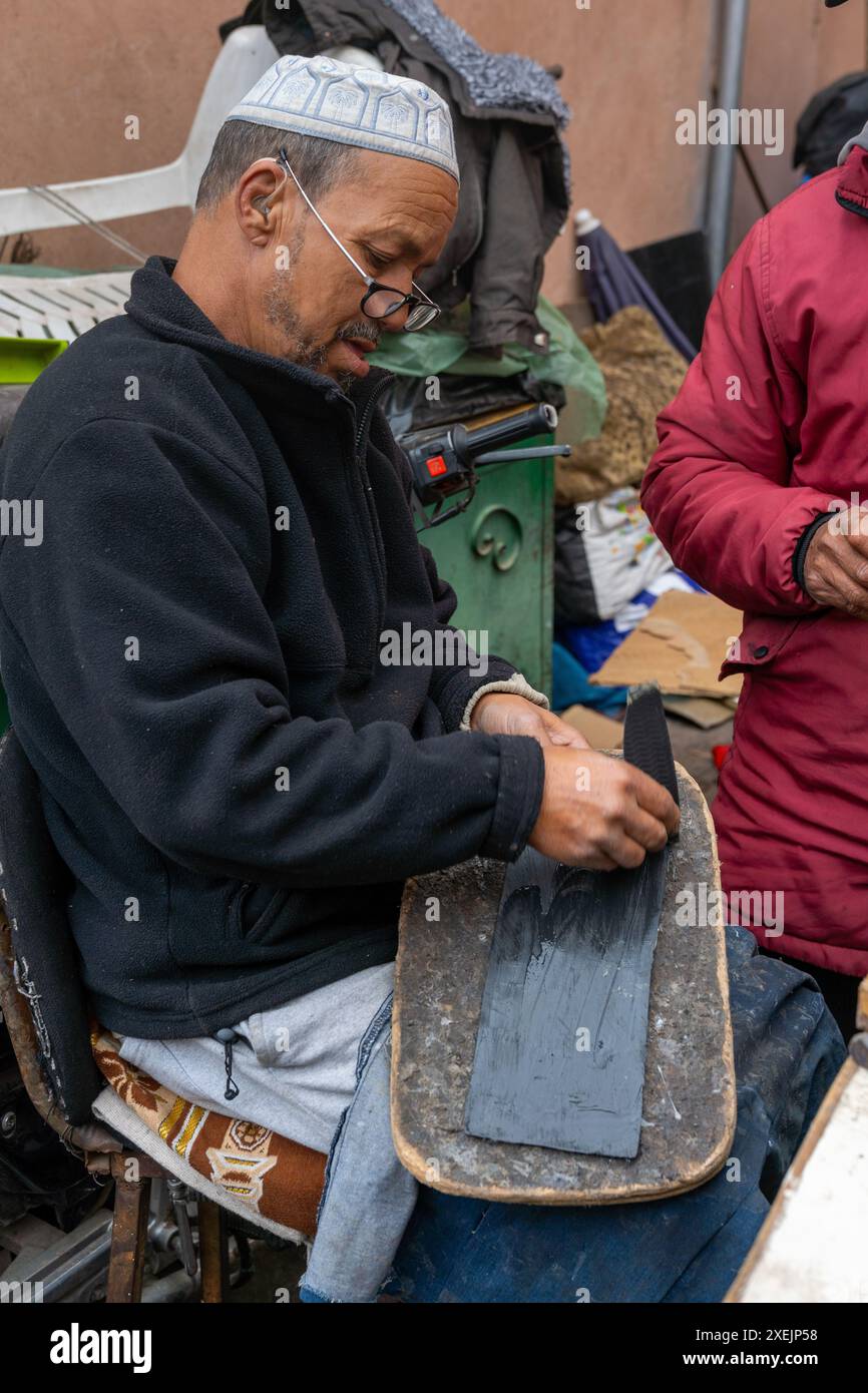 Traditionelle Schuhmacher im Souk der Medina von Marrakesch kleben neue Sohlen auf alte Schuhe Stockfoto