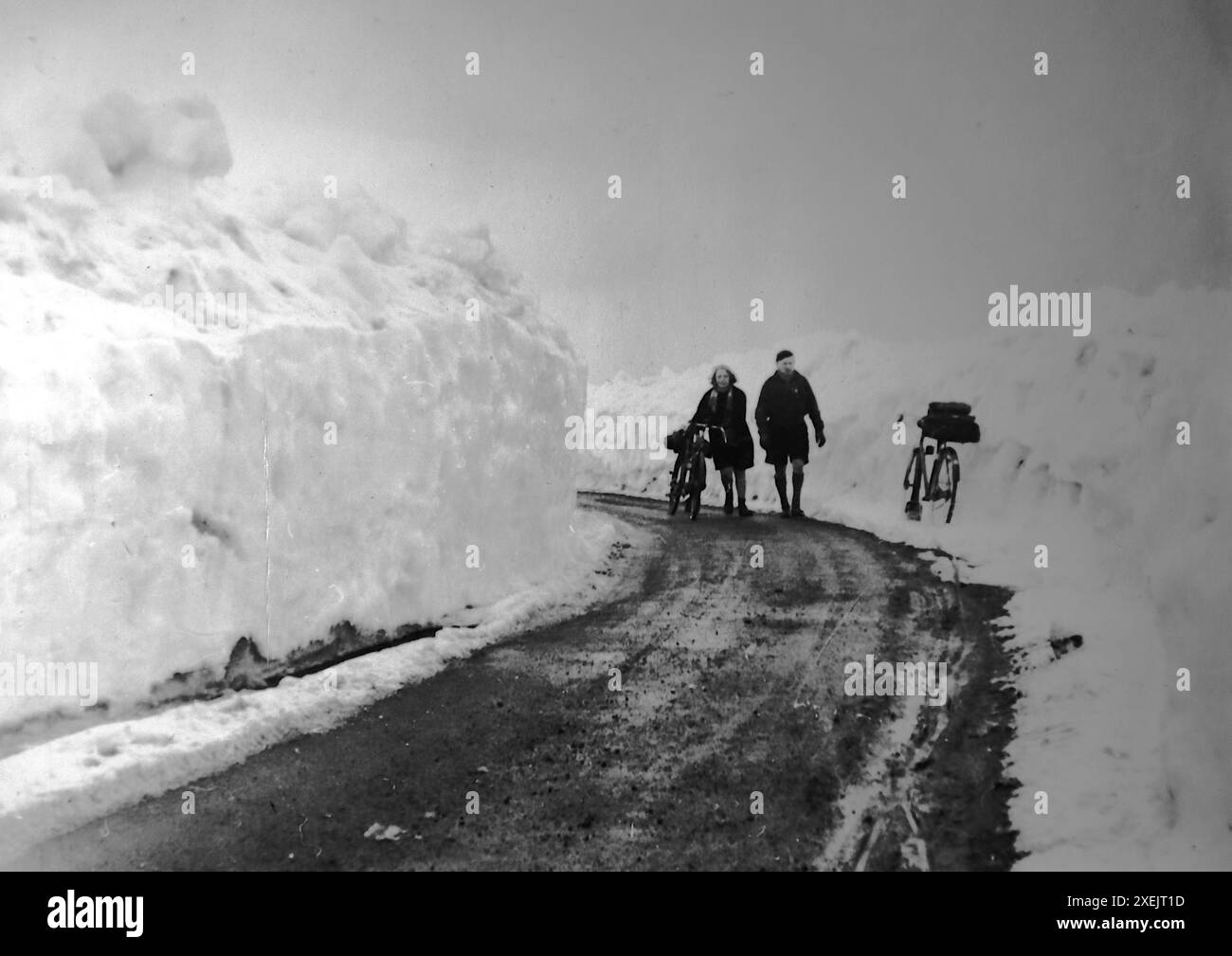 Ostern, Schnee weht in Fleet Moss, North Yorkshire, drei Wochen nach dem letzten Schneefall. Zwei Radfahrer, die zwischen den Drifts laufen. Radtour, 1937. Von einem Album, das eine Fahrradreise durch Großbritannien von einer Gruppe begeisterter Radfahrer umfasste. Das Album wurde von einem Amateurfotografen zusammengestellt und kommentiert und die Tour umfasste North Wales, Yorkshire, Lancashire und Cumbria. Es gab keinen Hinweis darauf, wer das Album komponiert hat. Die Größe der Originalfotos variierte, wobei die kleinsten ca. 3 x 2 Zoll, die größten ca. 7 x 5 Zoll waren. Stockfoto