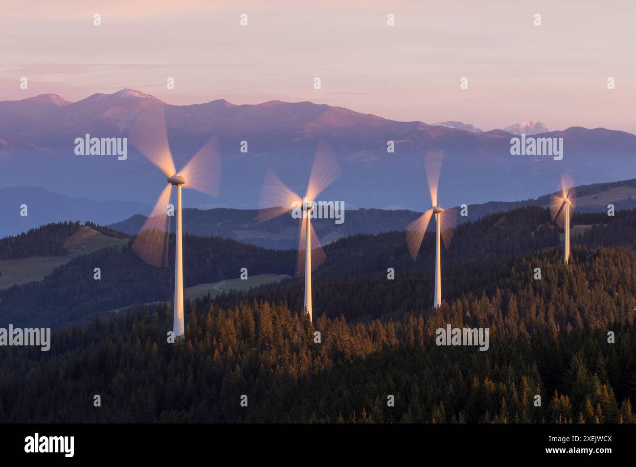 Eine Gruppe drehender Windmühlenkraftwerke auf einem Bergrücken im Morgenlicht Stockfoto