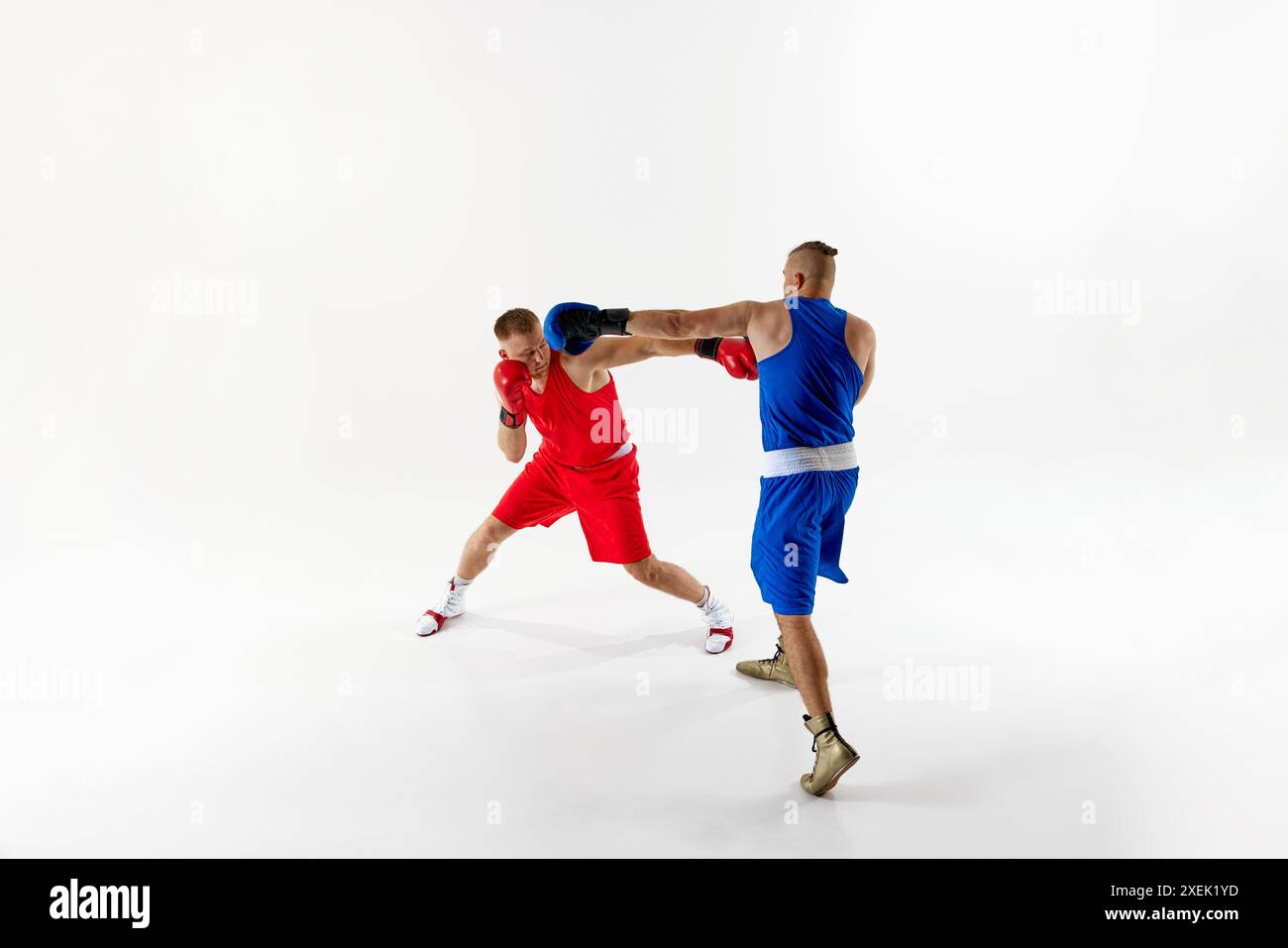 Trainingseinheit mit zwei engagierten Boxern, einer trägt rote und andere blaue Uniform, die beide ihre defensiven und offensiven Fähigkeiten verbessern. Stockfoto