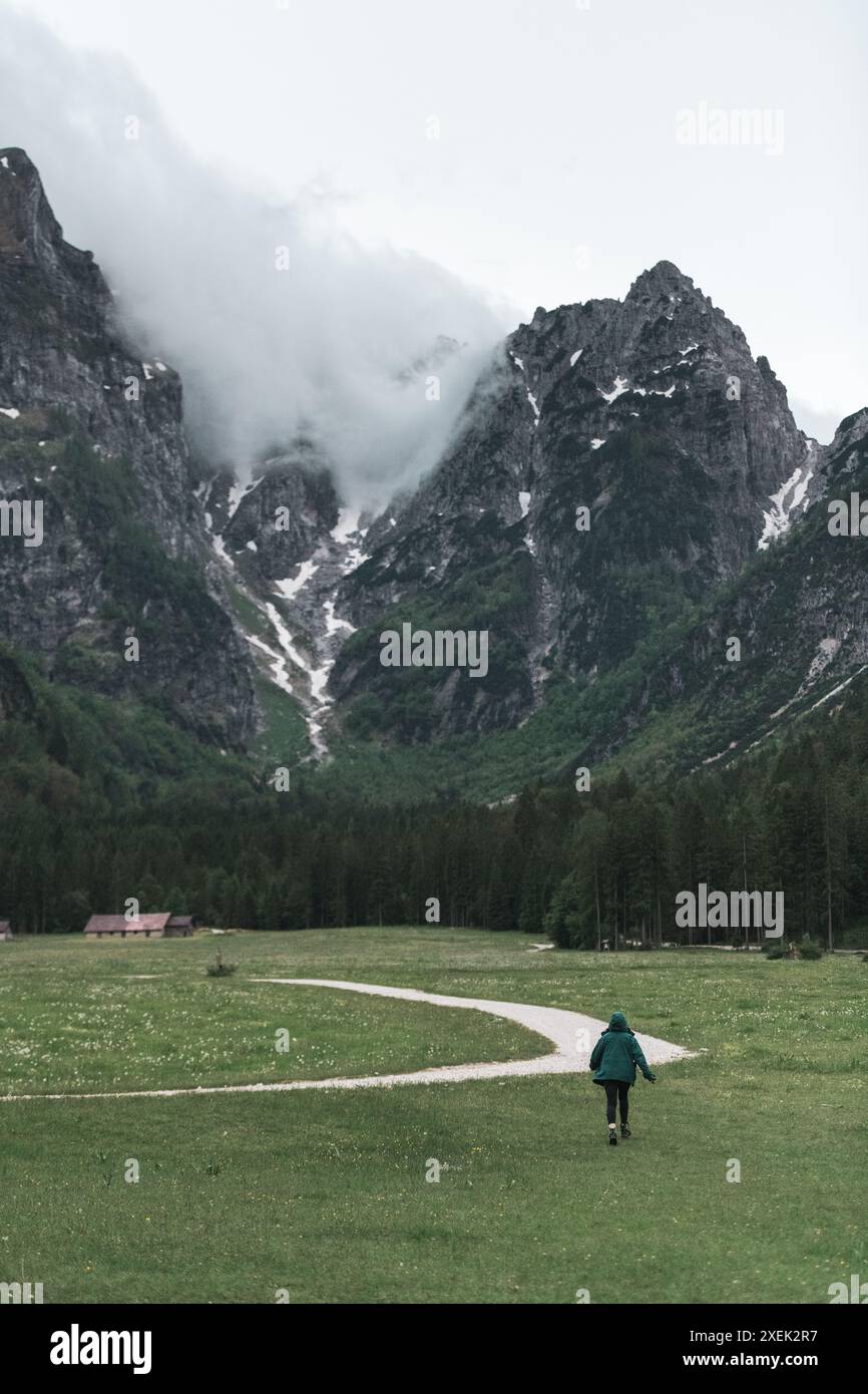 Fröhliche junge Frau, die durch die malerischen Wanderwege in den Alpen wandert Stockfoto