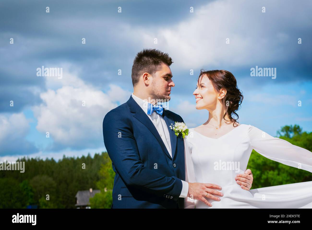 Glücklich litauischen Hochzeitspaar stehen zusammen im Freien in Smart Kleidung Pose mit trüben dramatischen blauen Himmel Hintergrund Stockfoto Glücklich litauischen Hochzeitspaar stehen zusammen im Freien in Smart Kleidung Pose mit trüben dramatischen blauen Himmel Hintergrund Stockfoto