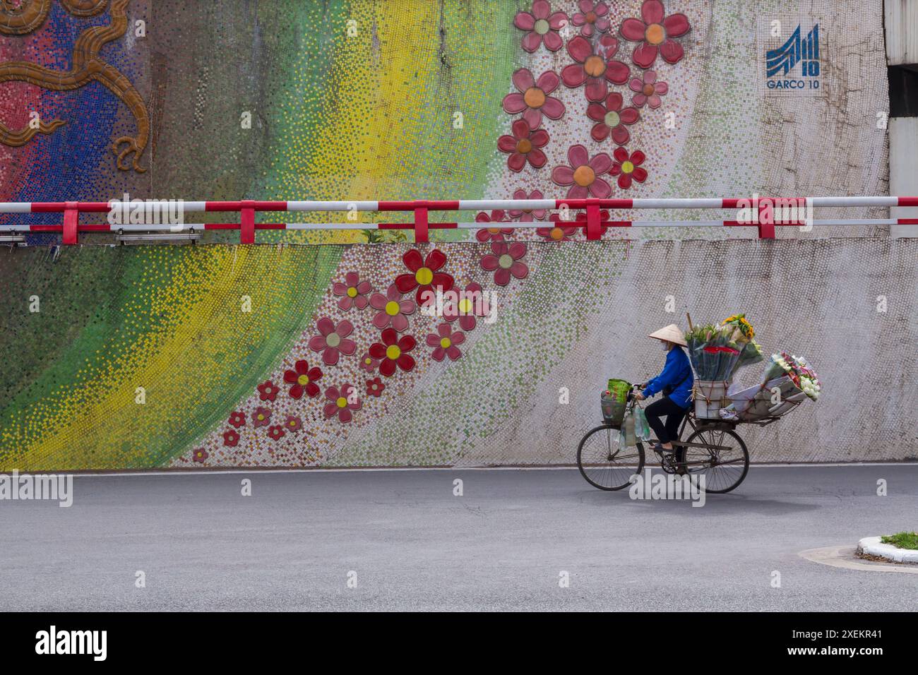 Blumenhändler Blumenhändler auf Fahrrad an Mosaikwand in Hanoi, Ha Noi, Nordvietnam, Asien im Juni Stockfoto