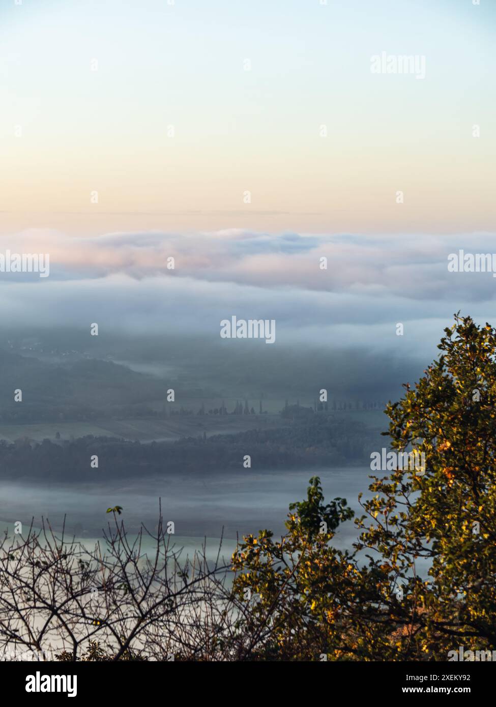 Dicker Nebel, niedrige Wolkendecke über landwirtschaftlichen Feldern, Straßen und Wäldern während eines Herbstsonnenaufgangs, schöne Farben, stimmungsvolle Landschaft in Ungarn Stockfoto