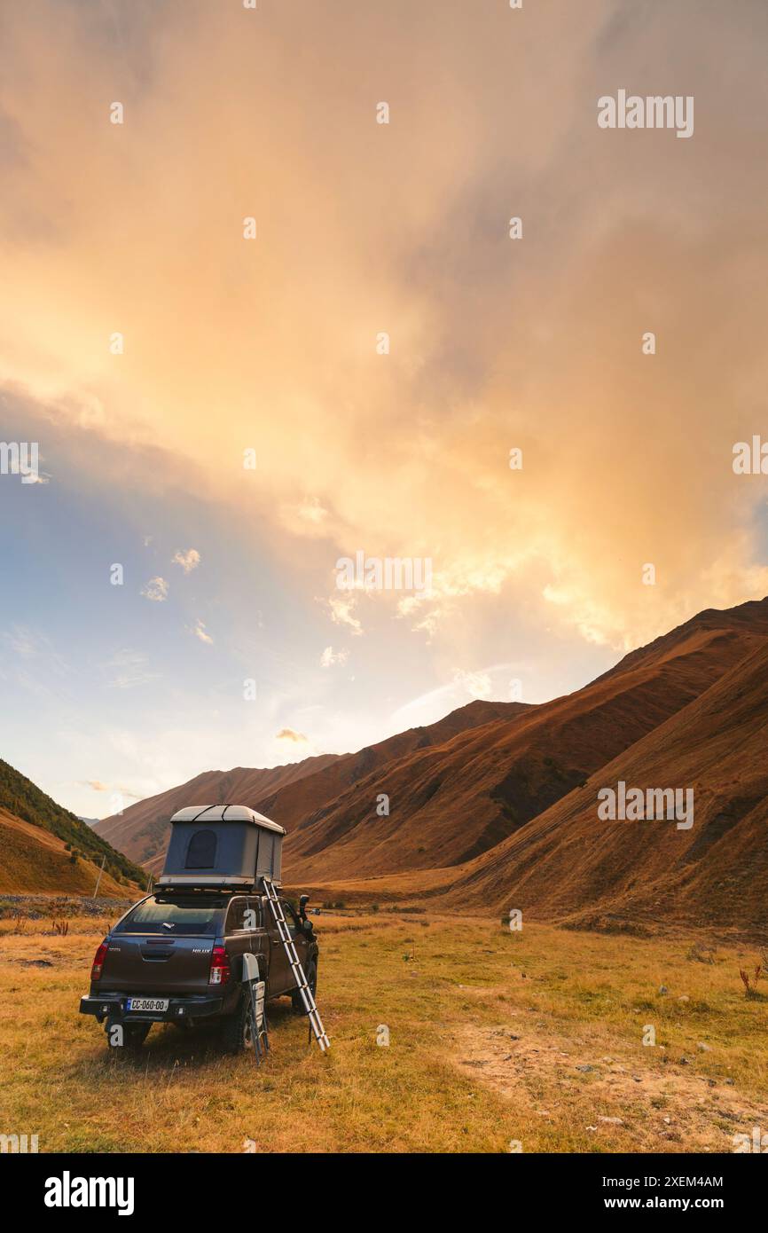 Sportfahrzeug mit Zeltstruktur auf dem Dach, das im Kazbegi-Nationalpark, Mzcheta-Mtianeti, Georgia, geparkt ist Stockfoto