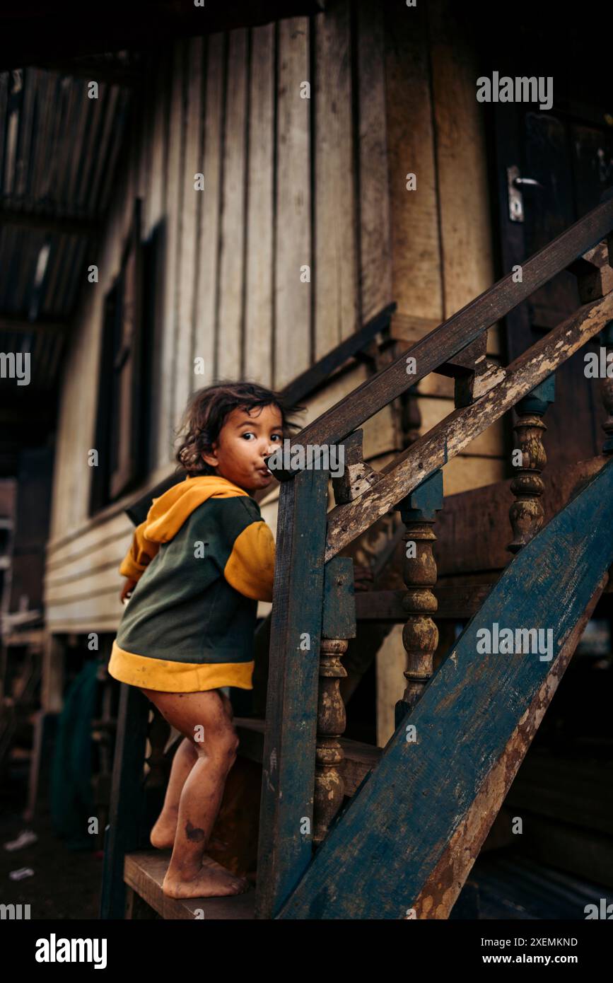 Das junge Mädchen steht auf den Stufen ihres Hauses in einem Dorf in Laos, Kok Phung Tai, Provinz Champasak, Laos Stockfoto