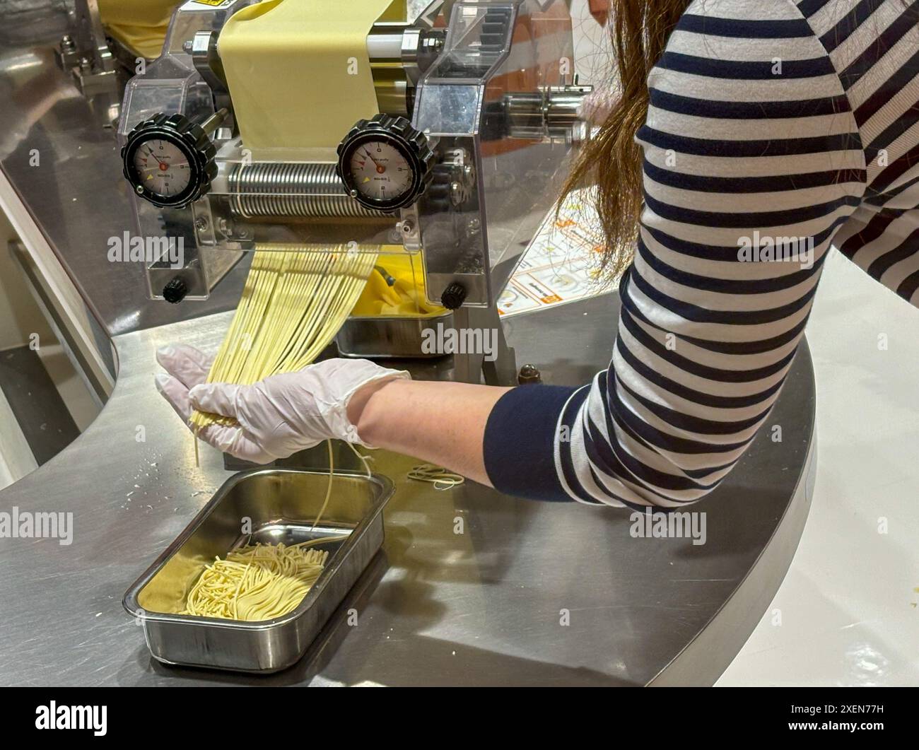 Ein Besucher sah, wie der Nudelteig während der Herstellung von Instant-Nudeln im CupNoodles Museum gerollt wurde. Das Museum widmet sich der Geschichte der Instant Nudeln und der Geschichte von Nissin Foods, gegründet von Momofuku Ando, dem Erfinder der Instant Nudeln und CupNudeln. Das Museum hat zwei Standorte, einen in Osaka und einen in Yokohama, Japan. Stockfoto