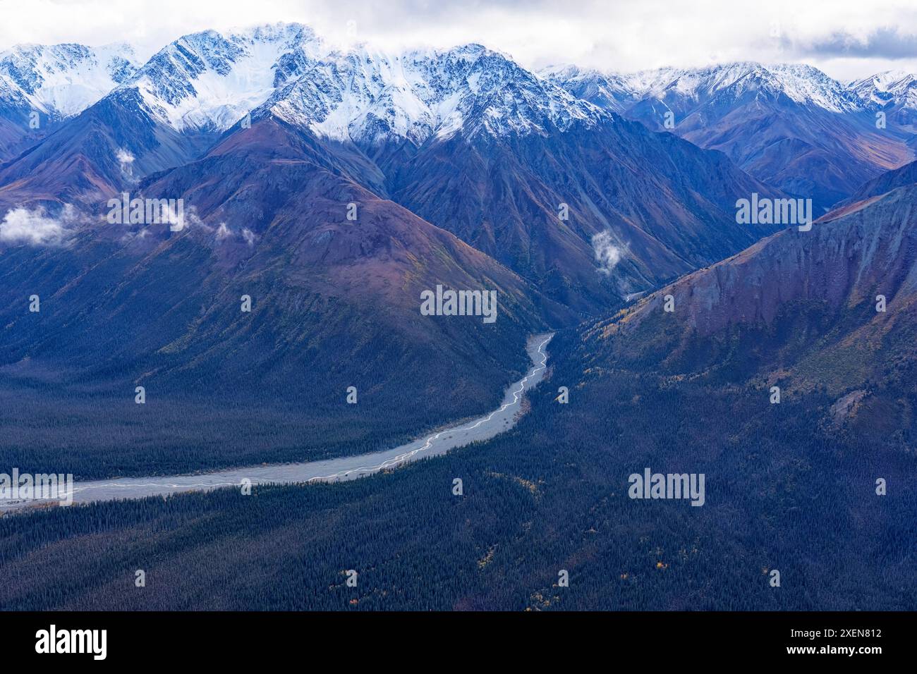 Aus der Vogelperspektive auf einen Fluss, der durch die schneebedeckten Berge fließt, und die Herbstlandschaft des Kluane National Park, aufgenommen während des Übergangs zwischen... Stockfoto