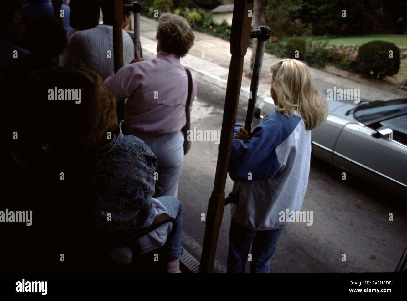 San Francisco CA., USA., Sommer 1995. Fahrt mit den historischen Cable Cars von San Francisco zur Fisherman's Wharf. Junge Leute, die mit der Seilbahn nach Fisherman's Wharf fahren. 9,7 Millionen Menschen fahren jährlich mit Seilbahnen. Der Bau einer Seilbahn ist eine anspruchsvolle Kunst, für die mehrere Dutzend Handwerker 18 bis 24 Monate benötigen. Straßenbahnen unterscheiden sich von Seilbahnen. Der zweite Weltkrieg eröffnete Arbeitsplätze für Afroamerikaner und Frauen in der Seilbahn. Die MUNI veranstaltet jedes Jahr einen Seilbahnwettbewerb. Die Seilbahnen sind das letzte manuell betriebene Seilbahnsystem der Welt. Stockfoto