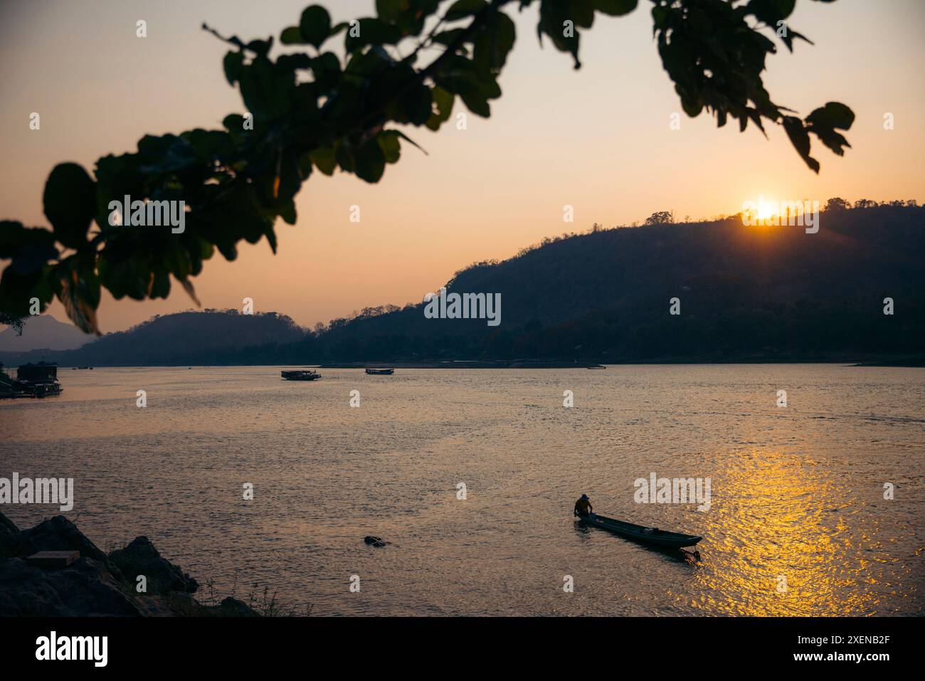 Sonnenuntergang über einem ruhigen Fluss und der Küste in Luang Prabang in Nordlaos; Luang Prabang, Provinz Luang Prabang, Laos Stockfoto