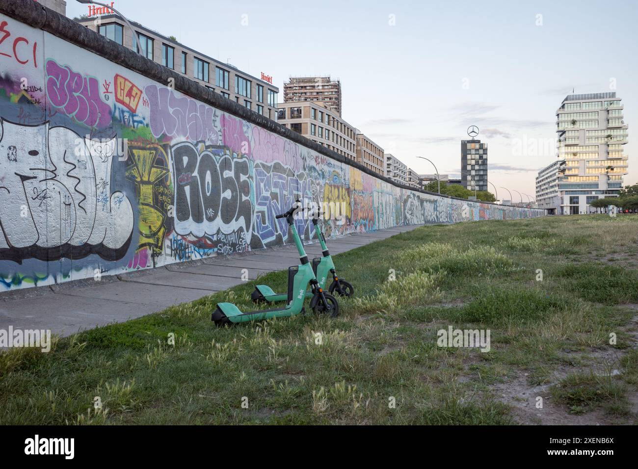 Bolt E-Scooter an der Berliner Mauer, Mühlenstraße, Berlin, Deutschland. Bewegungsfreiheit der Wand gegenüberstellen. Stockfoto