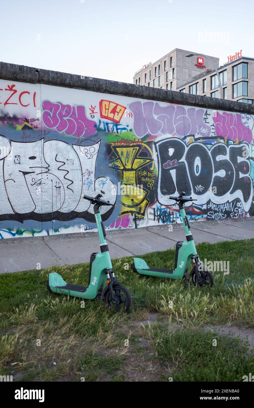 Bolt E-Scooter an der Berliner Mauer, Mühlenstraße, Berlin, Deutschland. Bewegungsfreiheit der Wand gegenüberstellen. Stockfoto