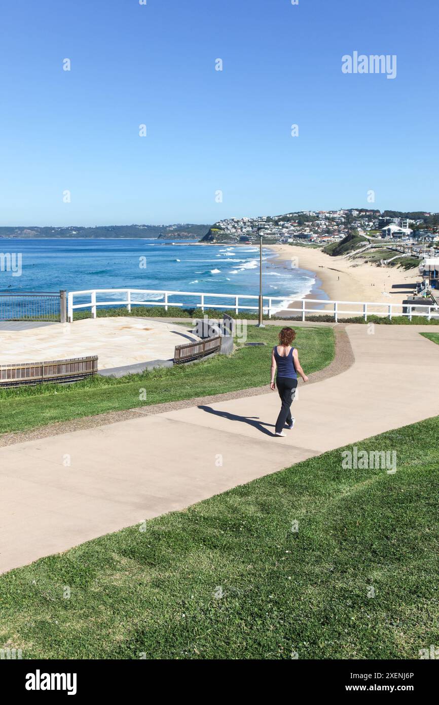 Eine Frau spaziert entlang des neu errichteten Küstenweges am Bar Beach - Newcastle Australia und an einem schönen sonnigen Herbsttag. Stockfoto