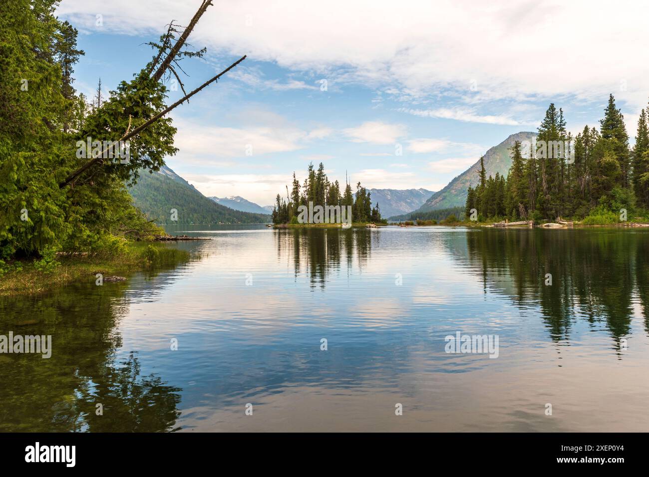 Ein horizontales Foto des Lake Wenatchee im Bundesstaat Washington, umgeben von immergrünen Bäumen und Cascade Mountains, die sich im ruhigen Seewasser spiegeln. Stockfoto