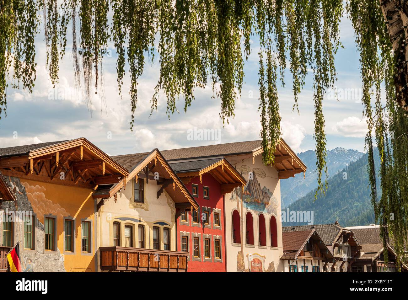 Die bayerische Stadt Leavenworth, Washington, besticht durch ihre Architektur im deutschen Stil mit einer Bergkulisse, die von grünen Laubblättern eingerahmt wird Stockfoto