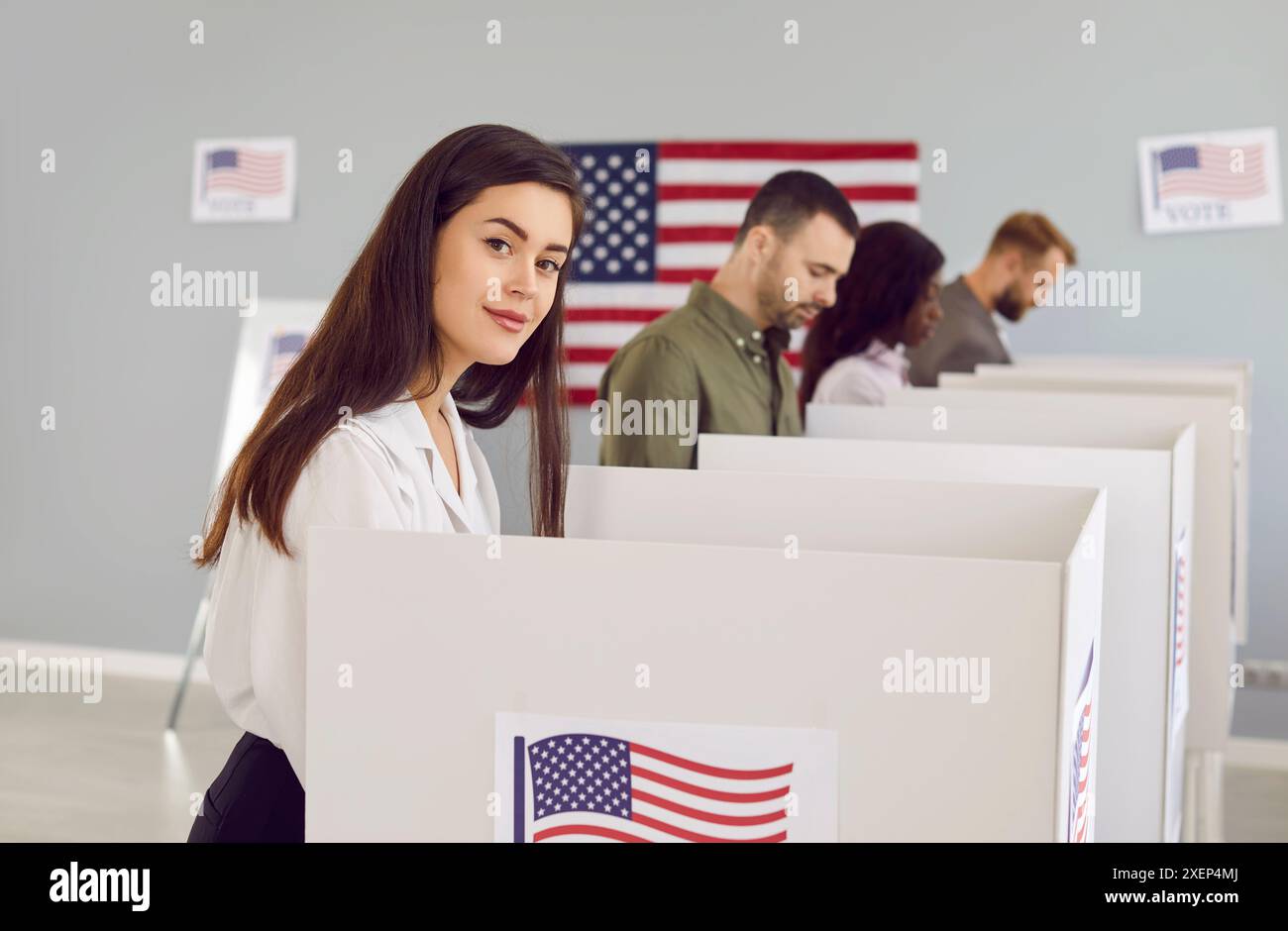 Junge amerikanische Frau stimmt bei demokratischen Präsidentschaftswahlen in Wahlkabinen ab Stockfoto