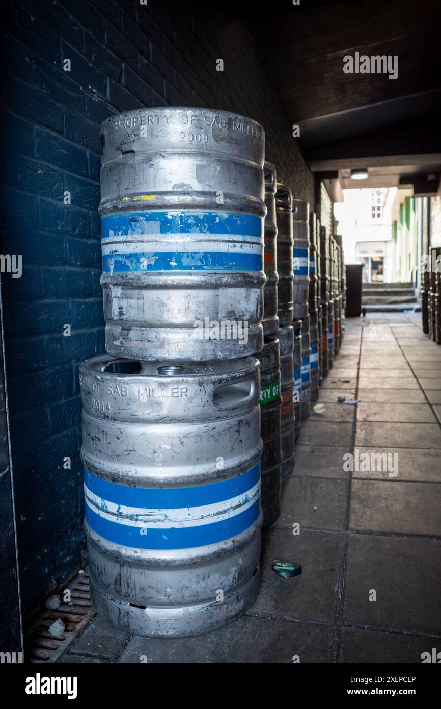 Enge Gasse zwischen zwei Gebäuden mit leeren, gestapelten Bierfässern Stockfoto