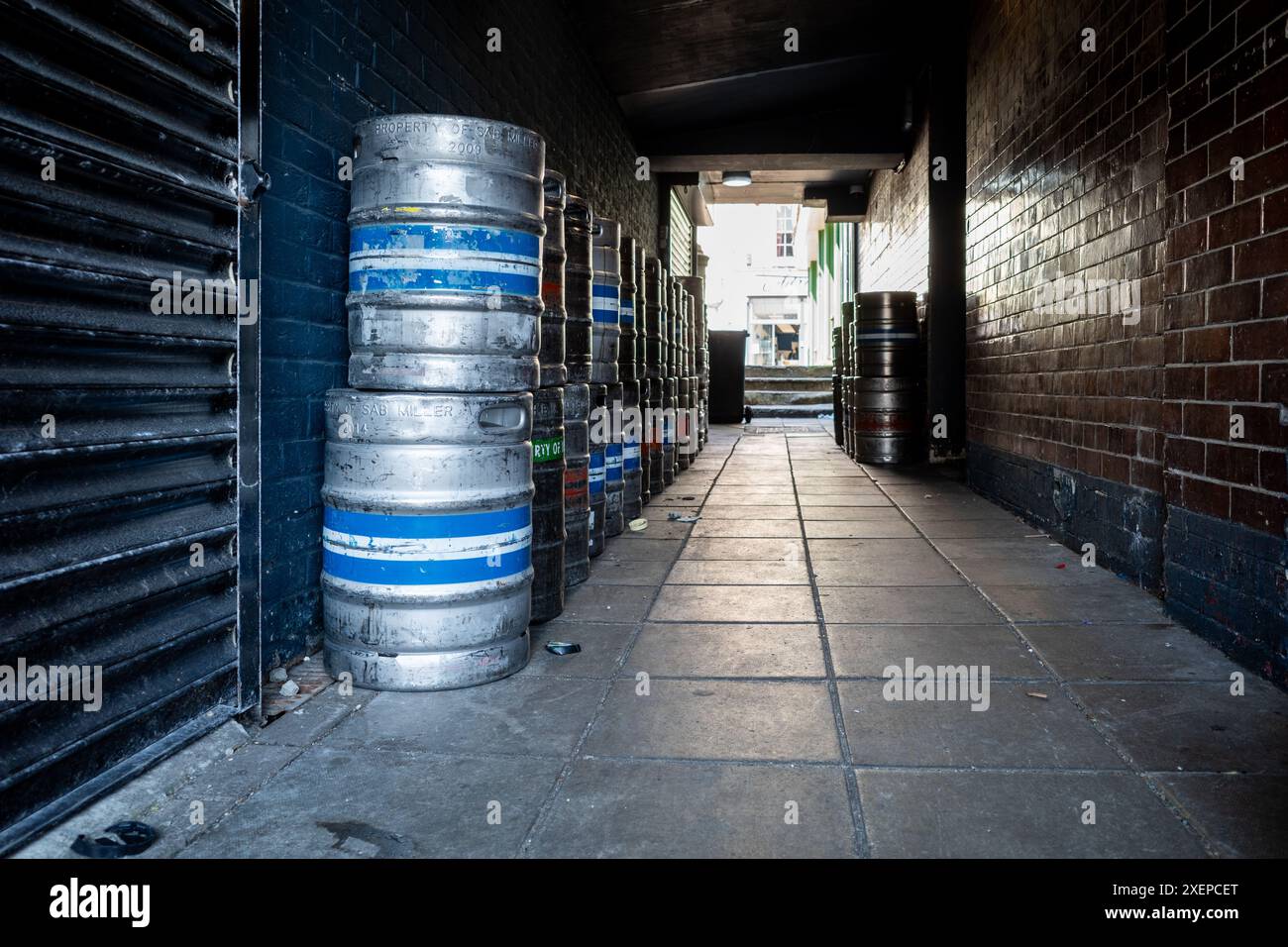 Enge Gasse zwischen zwei Gebäuden mit leeren, gestapelten Bierfässern Stockfoto