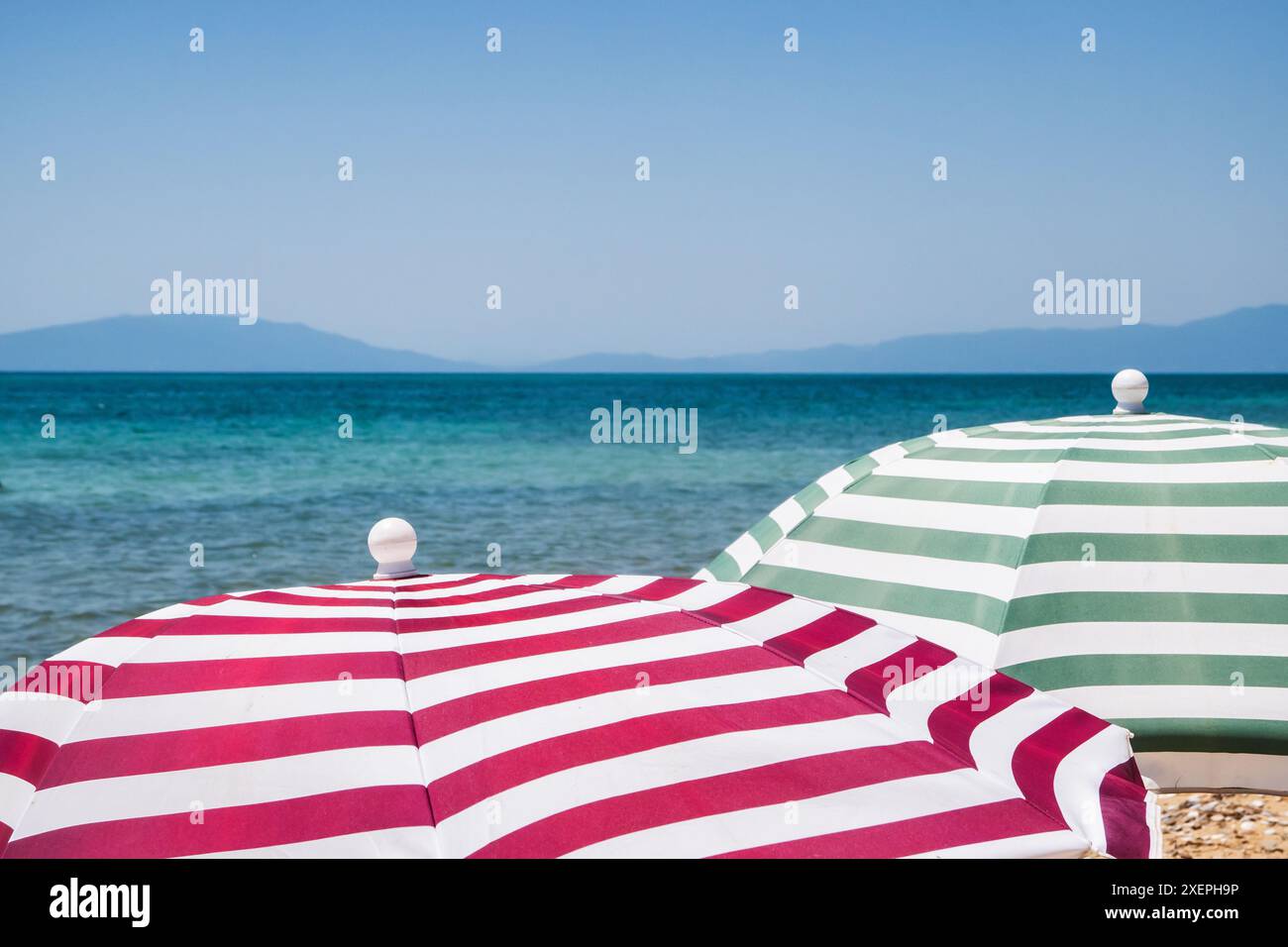 Gestreifte Sonnenschirme am Sandstrand in der Nähe des Meeres auf dem Sandstrand in der Nähe des Meeres Stockfoto