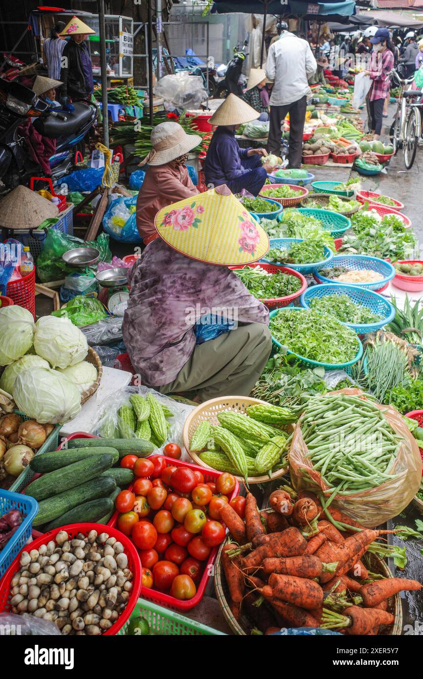 Hoi an, Vietnam - 5. Februar 2024: Obst- und Gemüsehändler mit traditionellen asiatischen konischen Hüten, Hoi an Market, Vietnam Stockfoto