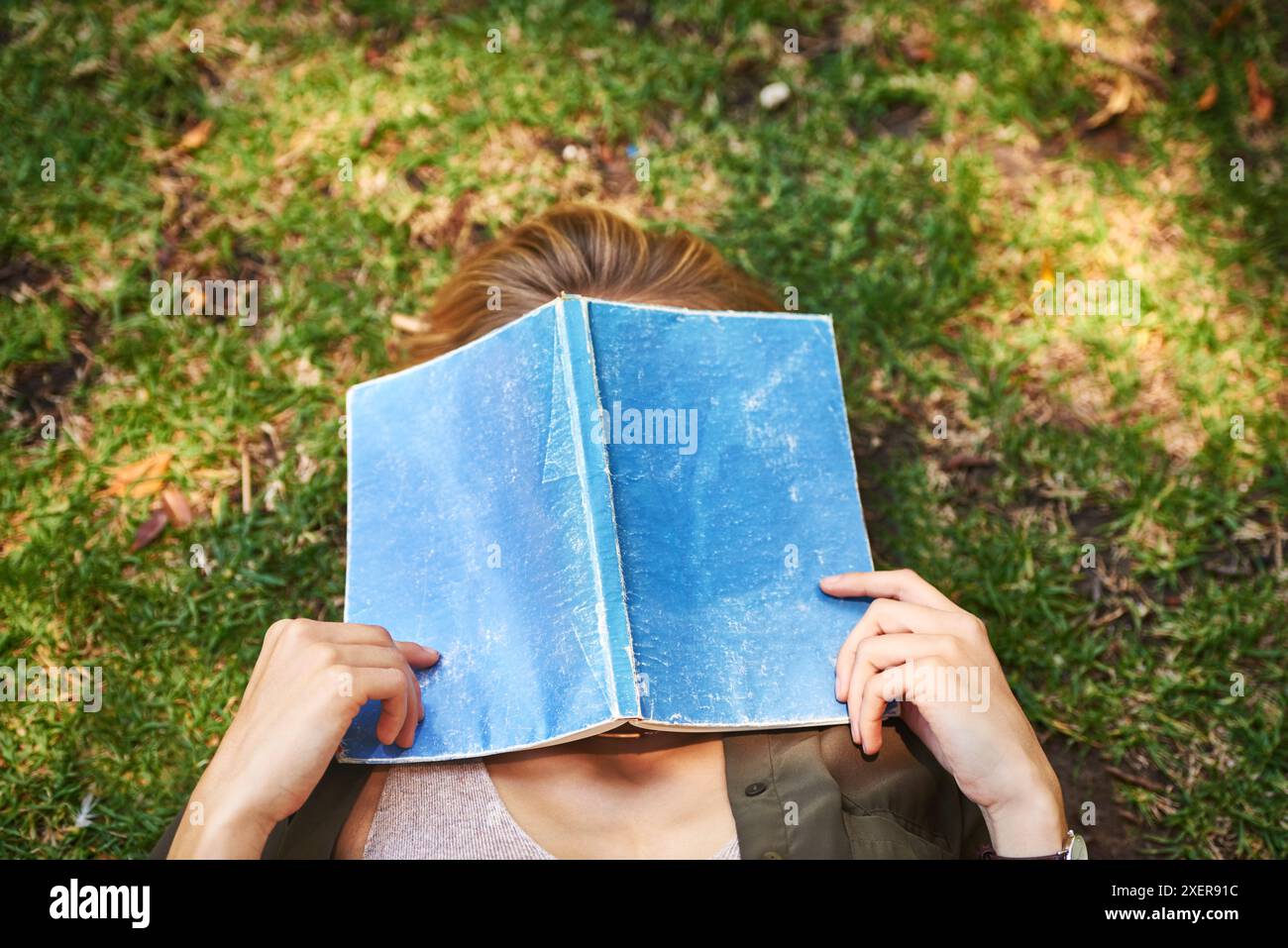 Mädchen, Garten und Cover Gesicht mit Buch auf Rasen zum Lesen, Fantasy und Romantik oder Liebespoesie. Frau, draußen und schlafend von Hobby für Romantik Stockfoto