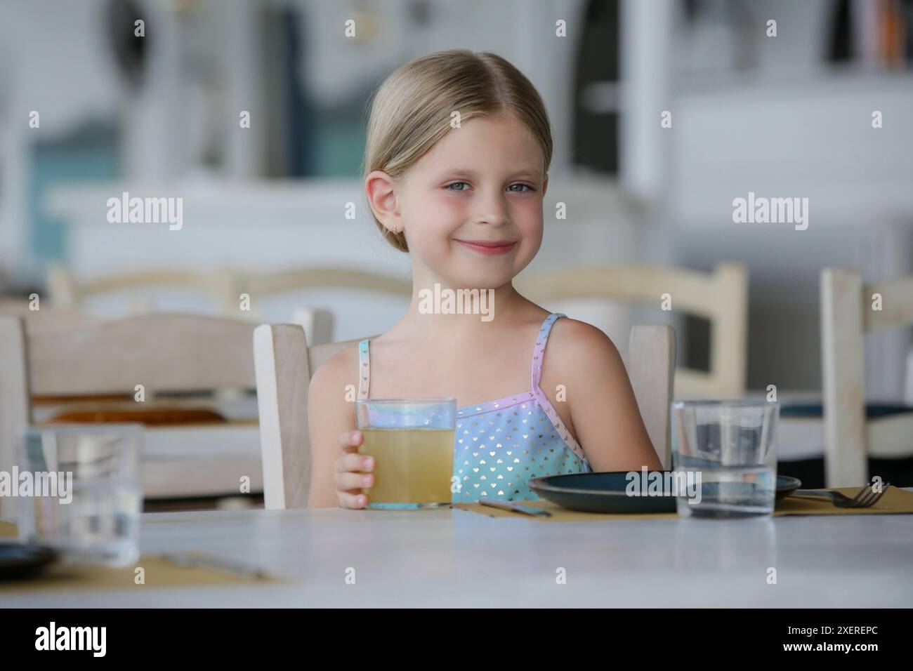 Ein entzückendes kleines Mädchen, das im Restaurant Saft trinkt Stockfoto