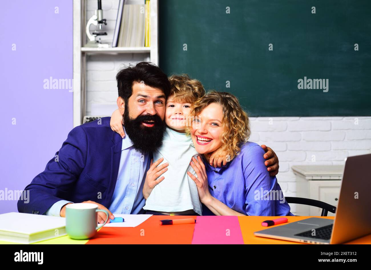 Erster Schultag. Ein lächelnder Schuljunge umarmt die Lehrer im Klassenzimmer. Bildung, Nachhilfe und Lernen für Kinder. Grundschüler Junge e Stockfoto