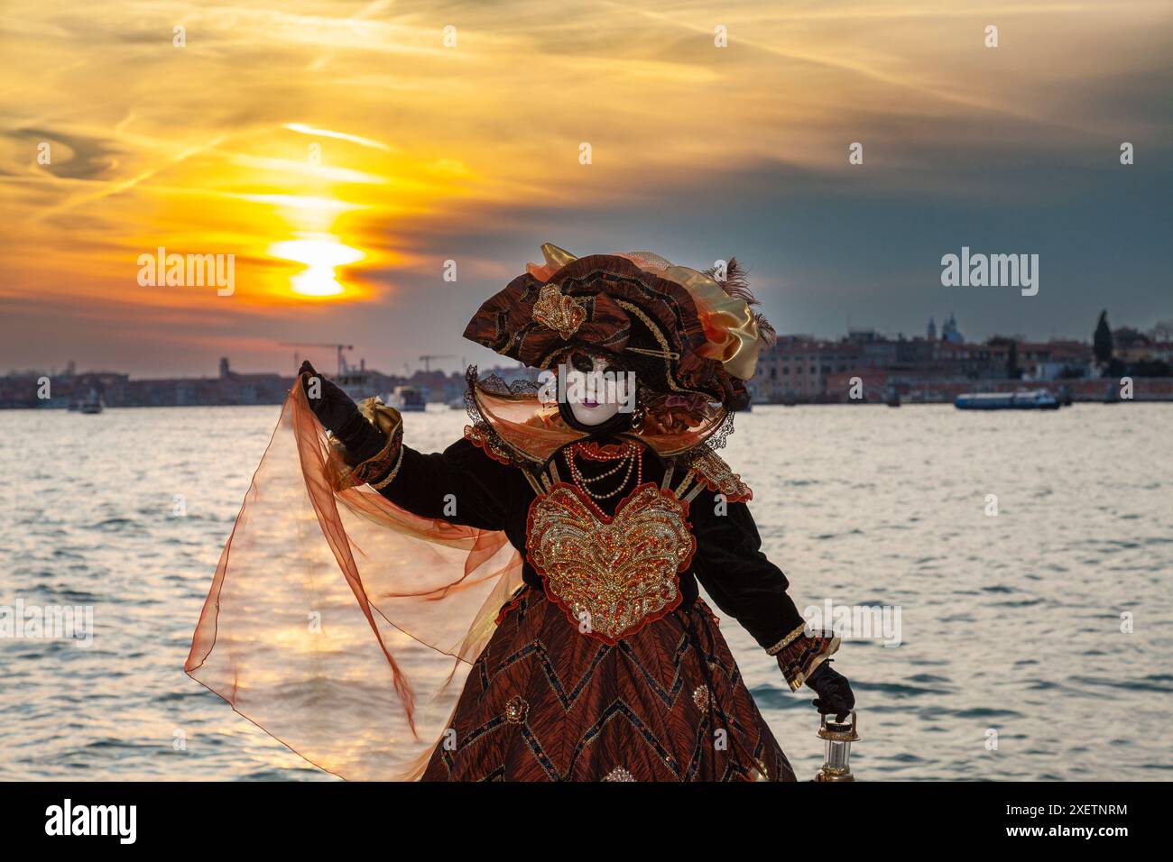 Karneval in Venedig Sonnenuntergang mit Frau in historischem Kostüm posiert vor der Lagune, Venedig, Venetien, Italien Stockfoto