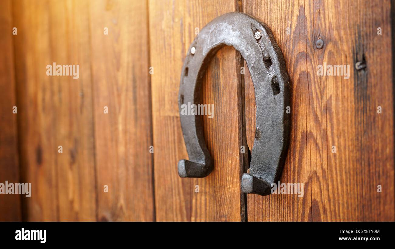 Ein Hufeisen für Glück hängt an einer Holztür. Symbol für Glück und Glück. Ein eisernes Glückshufeisen - ein Talisman-Aberglaube für Glück. Stockfoto Ein Hufeisen für Glück hängt an einer Holztür. Symbol für Glück und Glück. Ein eisernes Glückshufeisen - ein Talisman-Aberglaube für Glück. Stockfoto