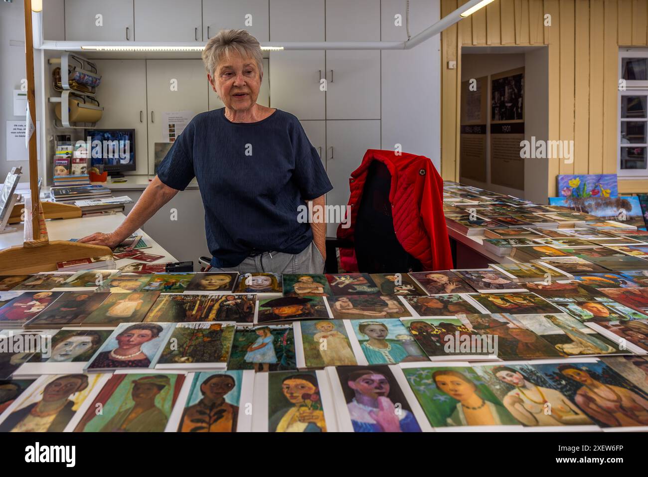 Sigrun Kaufmann steht an einem Tisch, der mit Postkartenformaten Selbstporträts von Paula Modersohn-Becker im Museum am Modersohn-Haus in Worpswede ausgebreitet ist. Ihr Ehemann Wolfgang Kaufmann baute die Sammlung des Museums auf, die auch Werke von Otto Modersohn, Fritz Mackensen und Heinrich Vogeler umfasst. Worpswede, Niedersachsen, Deutschland. Stockfoto