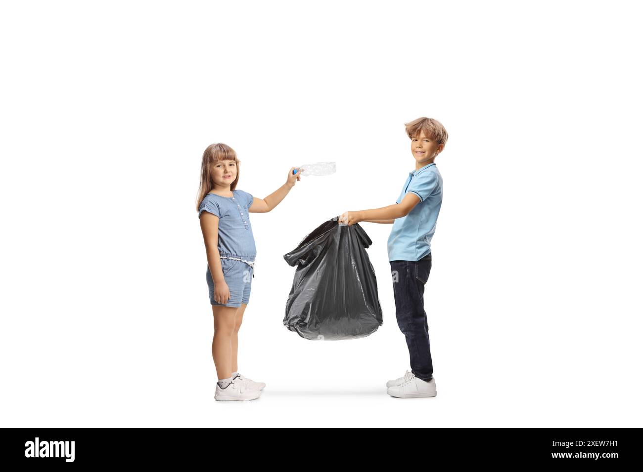 Ein Junge, der einen Müllsack hält und ein Mädchen, das eine Plastikflasche isoliert auf weißem Hintergrund wirft Stockfoto