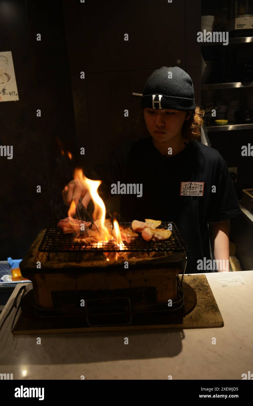 Ein junger Japaner, der Spieße im Restaurant Washio Yakitori Izakaya in Chuocho, Kagoshima, Japan grillt. Stockfoto