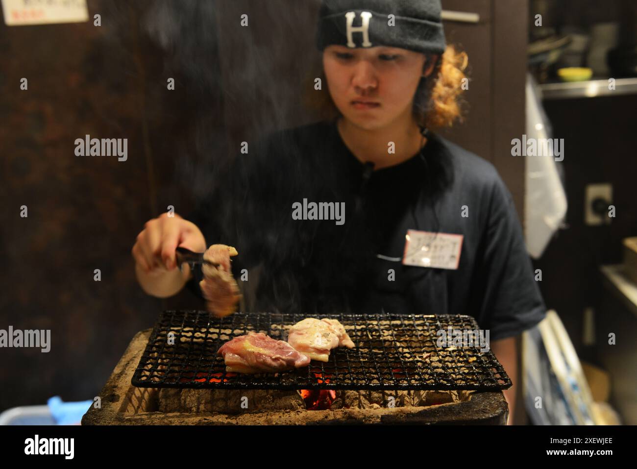 Ein junger Japaner, der Spieße im Restaurant Washio Yakitori Izakaya in Chuocho, Kagoshima, Japan grillt. Stockfoto