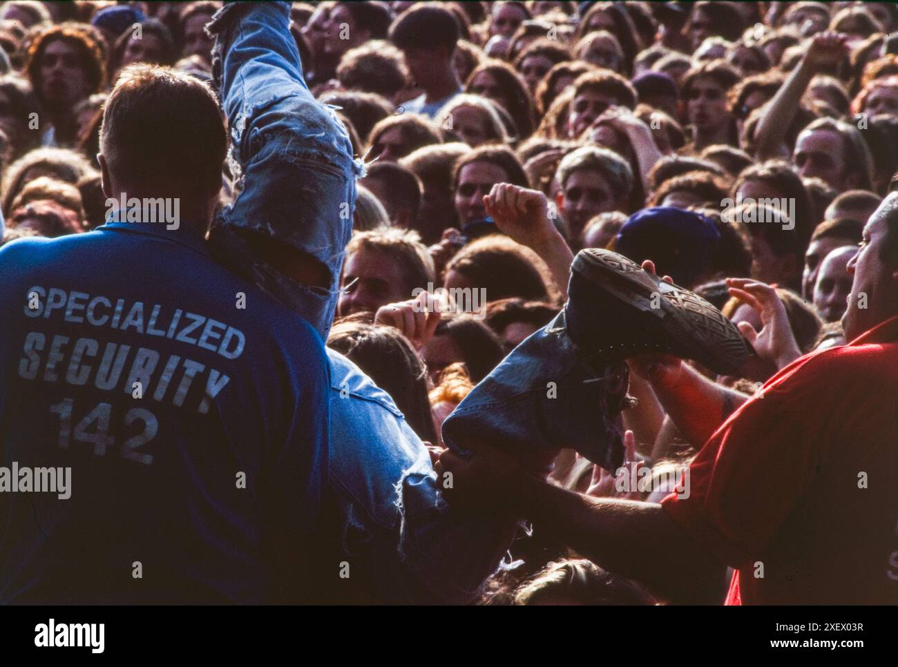 Reading, UK, August 1994: Sicherheitspersonal helfen den Zuschauern beim Reading Festival im August 1994 über die Bühnenbarriere. Das 1961 als National Jazz Festival gegründete Festival zog 1971 in sein festes Zuhause auf Little John's Farm in Reading um und findet am Feiertagswochenende im August in Großbritannien statt. Stockfoto