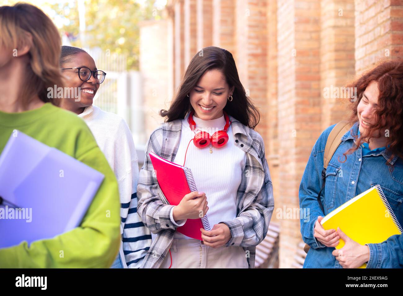 Multiethnische Gruppe von Schülern, die mit Notizbüchern laufen, lachen. Stockfoto