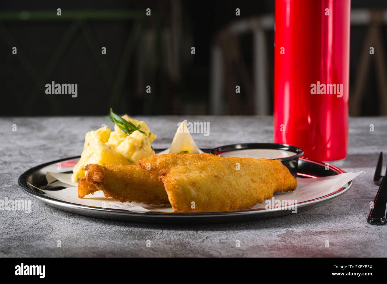 Frittiertes, beschichtetes Fischfilet mit Kartoffelsalat auf Steintisch Stockfoto