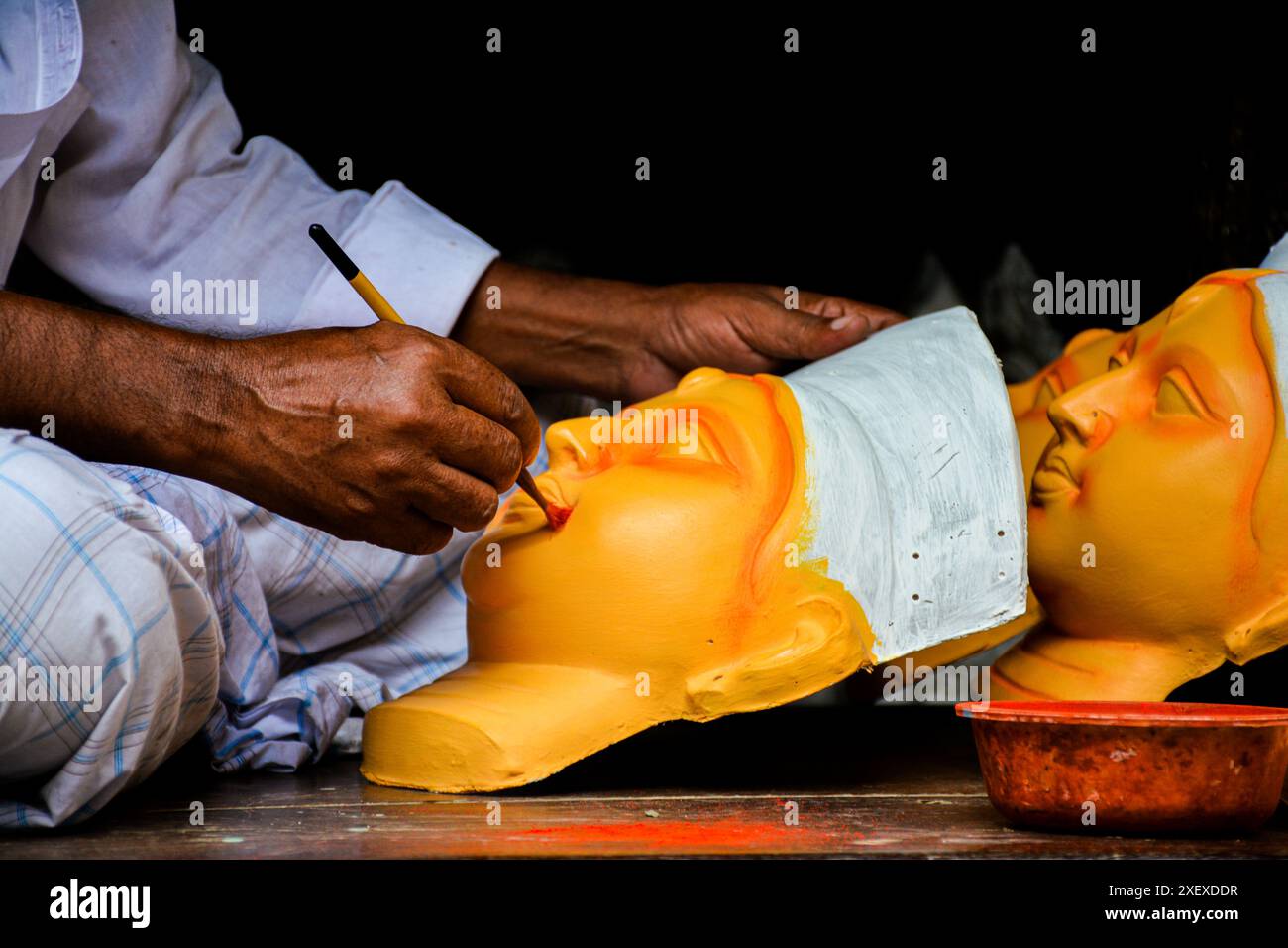 Das Bild aus Kumortuli, Kalkutta, zeigt ein handwerkliches Gemälde des Kopfes der Göttin Durga mit einem Pinsel. Das Bild zeigt den Prozess der Idol-Herstellung. Stockfoto