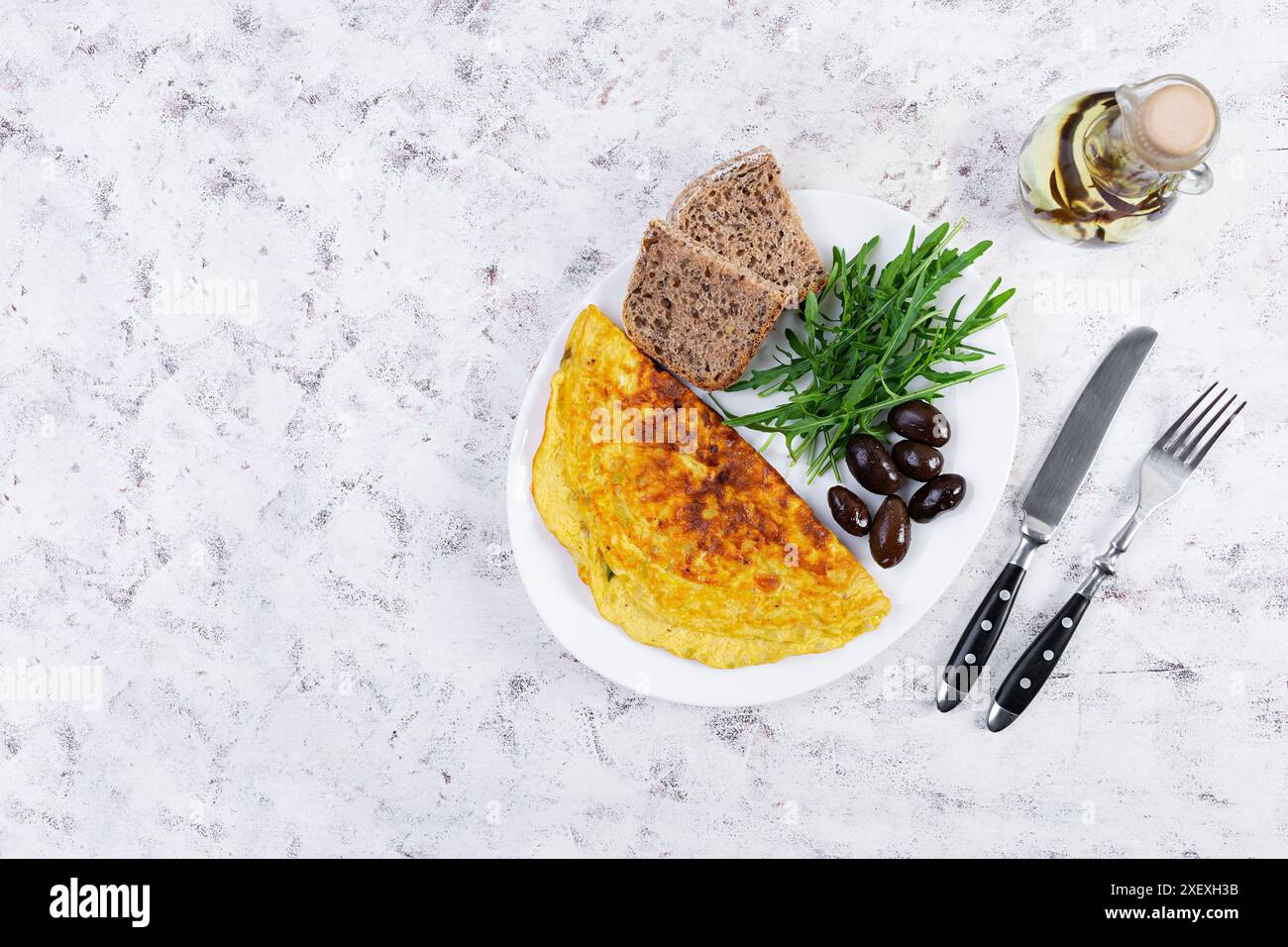 Gebratenes Omelette mit Zwiebeln, Kräutern und Oliven. Leckeres Frühstück mit Eiern und Toast Stockfoto