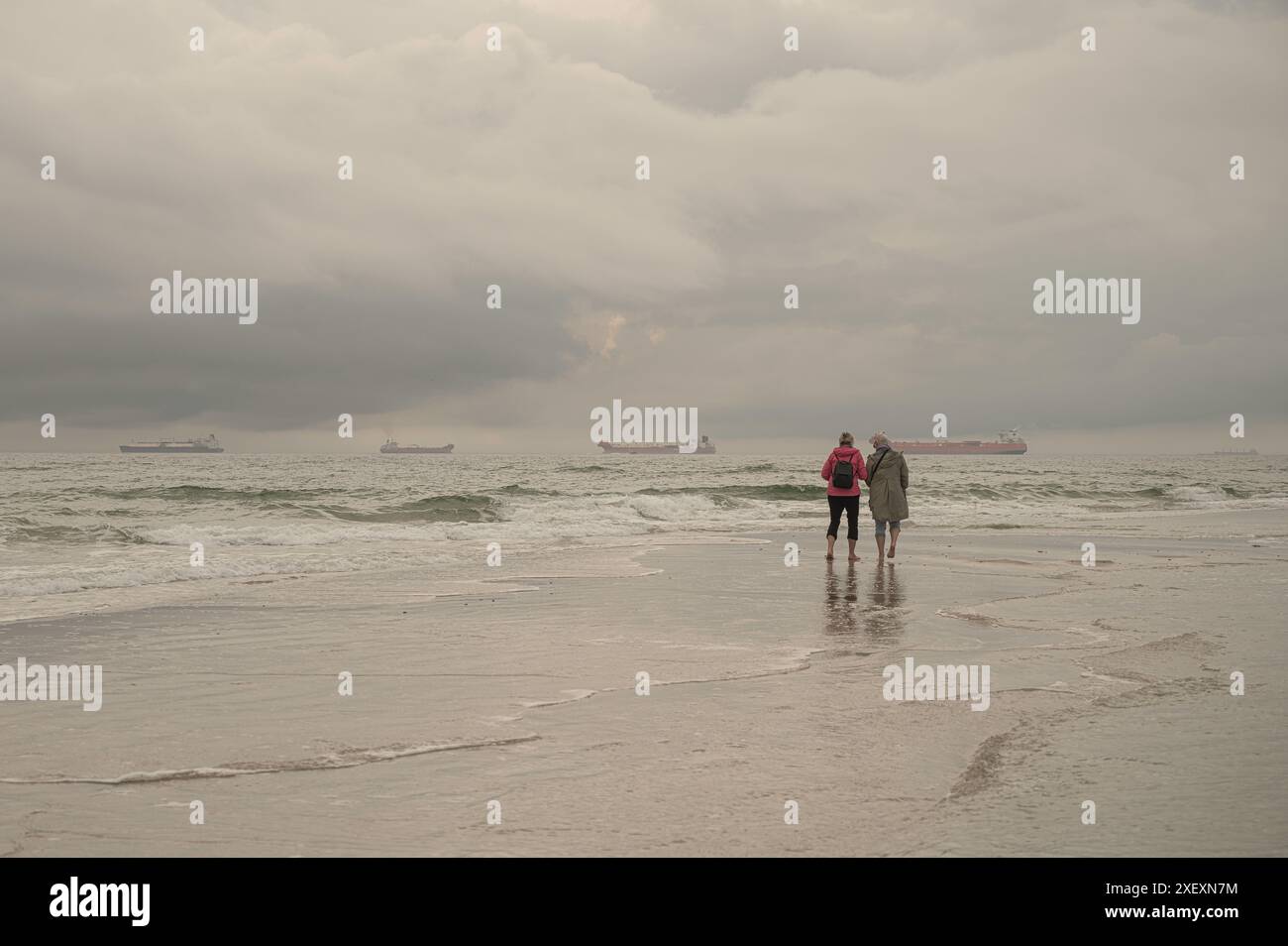 Zwei Frauen stehen auf dem obersten Gipfel dänemarks bei Grenen und beobachten Schiffe, die vorbeisegeln, Skagen, Dänemark, 30. Mai 2024 Stockfoto