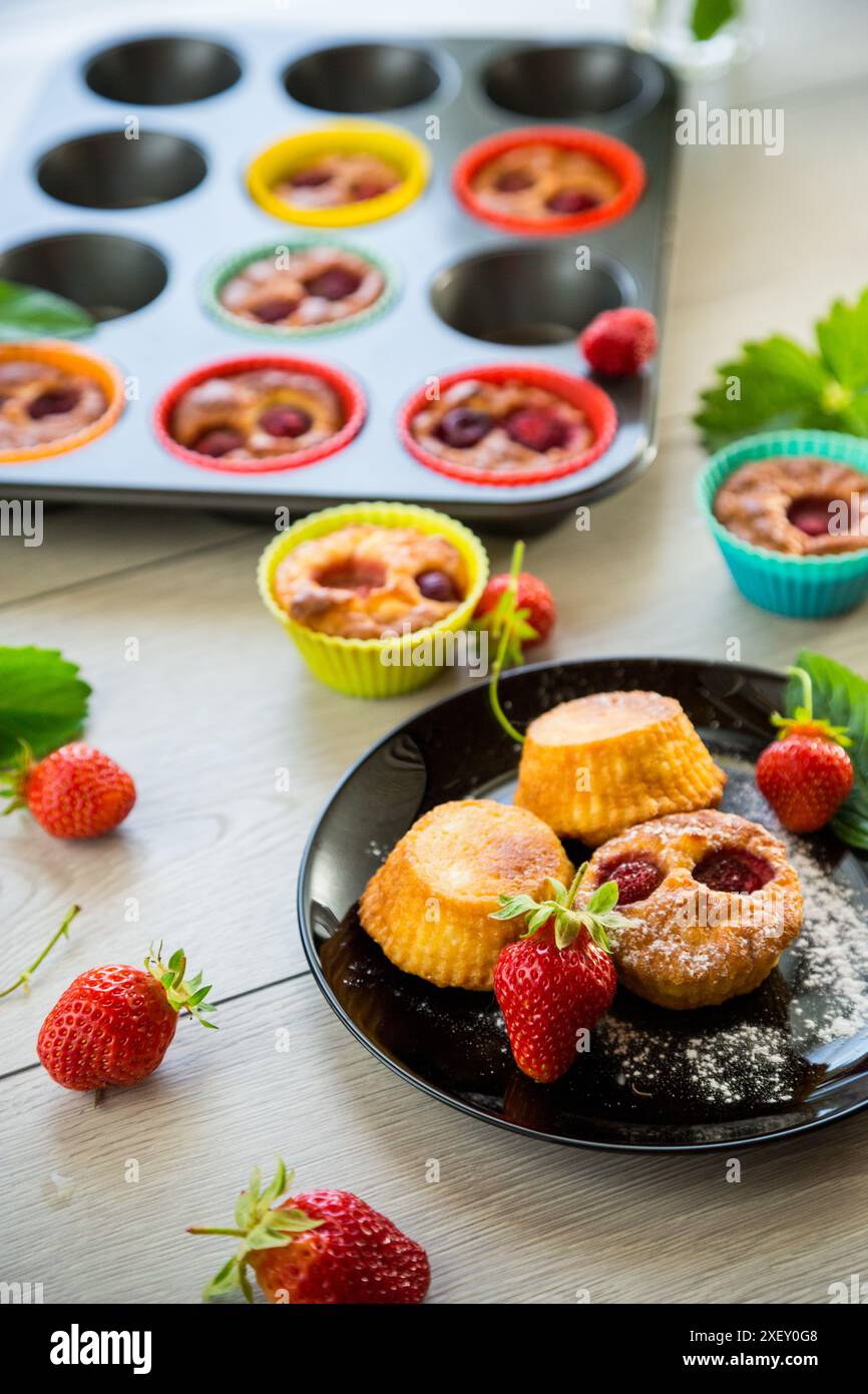 Süße Quark-Muffins mit Erdbeerfüllung, auf einem Teller auf einem Holztisch. Stockfoto