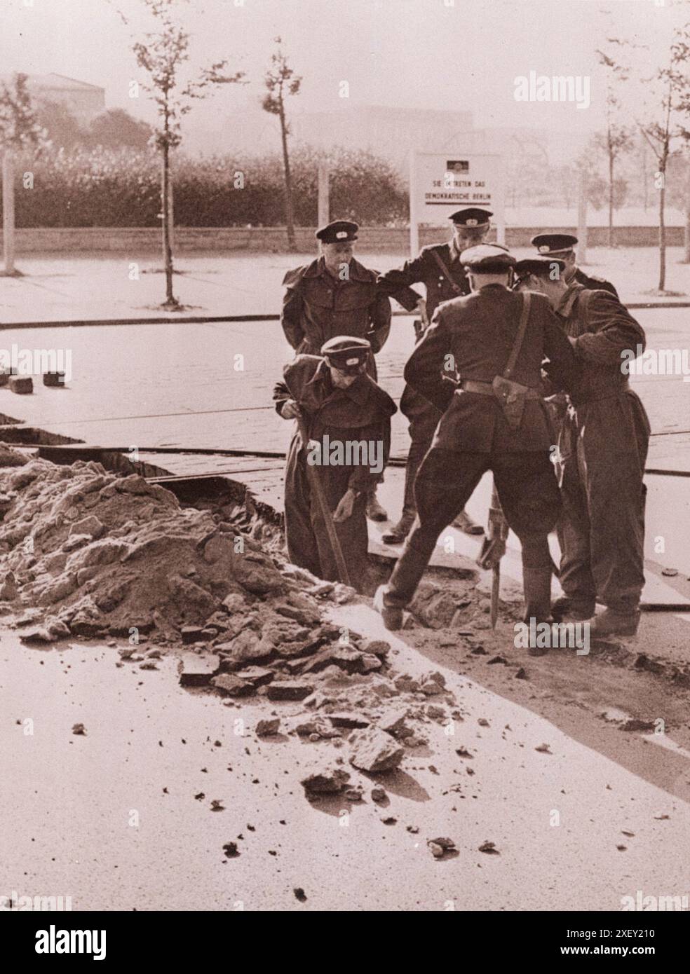 Vintage-Foto der Berliner Krise von 1961: Mauerbau DDR-Polizei zerreißt Pflaster nahe dem Potsdamerplatz, um einen dauerhaften Straßenblock zu bauen. Kommunistisch Aufgerichtet Im Hintergrund Steht: "Du Kommst Ins Demokratische Berlin." Berlin, August 1961 Stockfoto
