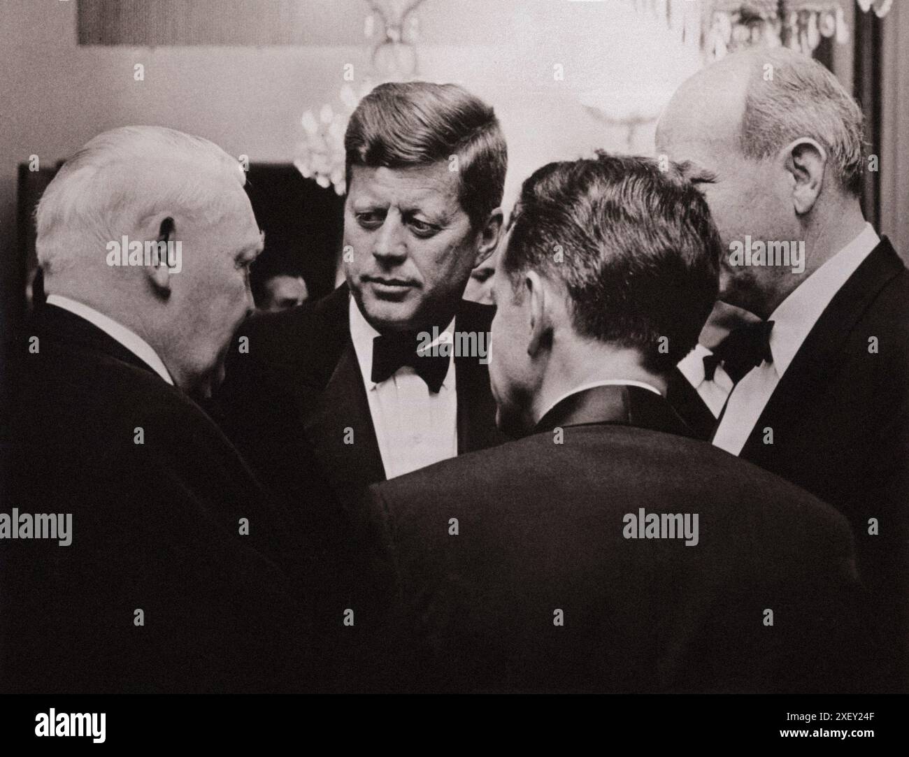 Vintage-Foto der Berliner Krise von 1961: Mauerbau. Vizekanzler Ludwig Erhard (links) spricht mit Präsident Kennedy und US-Außenminister Dean Rusk (rechts) bei einem Abendessen von Bundeskanzler Konrad Adenauer. Robert H. Lochner, Direktor von RIAS, dem US-Radiosender in West-Berlin (zurück zur Kamera), fungiert als Dolmetscher. Bundesrepublik Deutschland. Juni 1963 Stockfoto