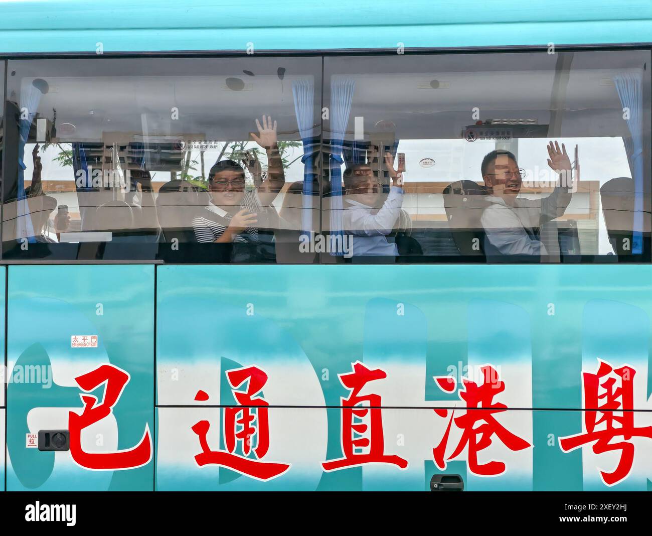 (240630) -- SHENZHEN, 30. Juni 2024 (Xinhua) -- Passagiere winken an Bord eines Busses an einer Mautstation der Shenzhen-Zhongshan-Verbindung in der südchinesischen Provinz Guangdong, 30. Juni 2024. Der Shenzhen-Zhongshan Link, eine riesige Überseepassage in Südchina mit zwei Brücken, zwei künstlichen Inseln und einem Unterwassertunnel, wurde am Sonntag um 15 Uhr für den Verkehr geöffnet. Die 24 km lange Verbindung verkürzt die Reisezeit zwischen der Stadt Zhongshan und dem Technologieknotenpunkt Shenzhen, der sich auf der gegenüberliegenden Seite der Mündung des Perlflusses in der Provinz Guangdong befindet, drastisch, wodurch die Dauer der Reise verkürzt wird Stockfoto