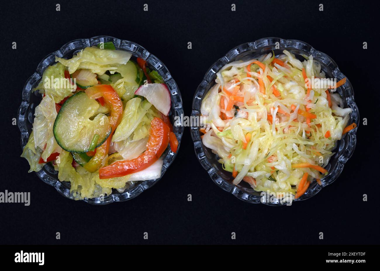 Gemüsesalat in einer Salatschale aus Glas auf schwarzem Hintergrund. Eine Portion Gemüsesalat. Stockfoto