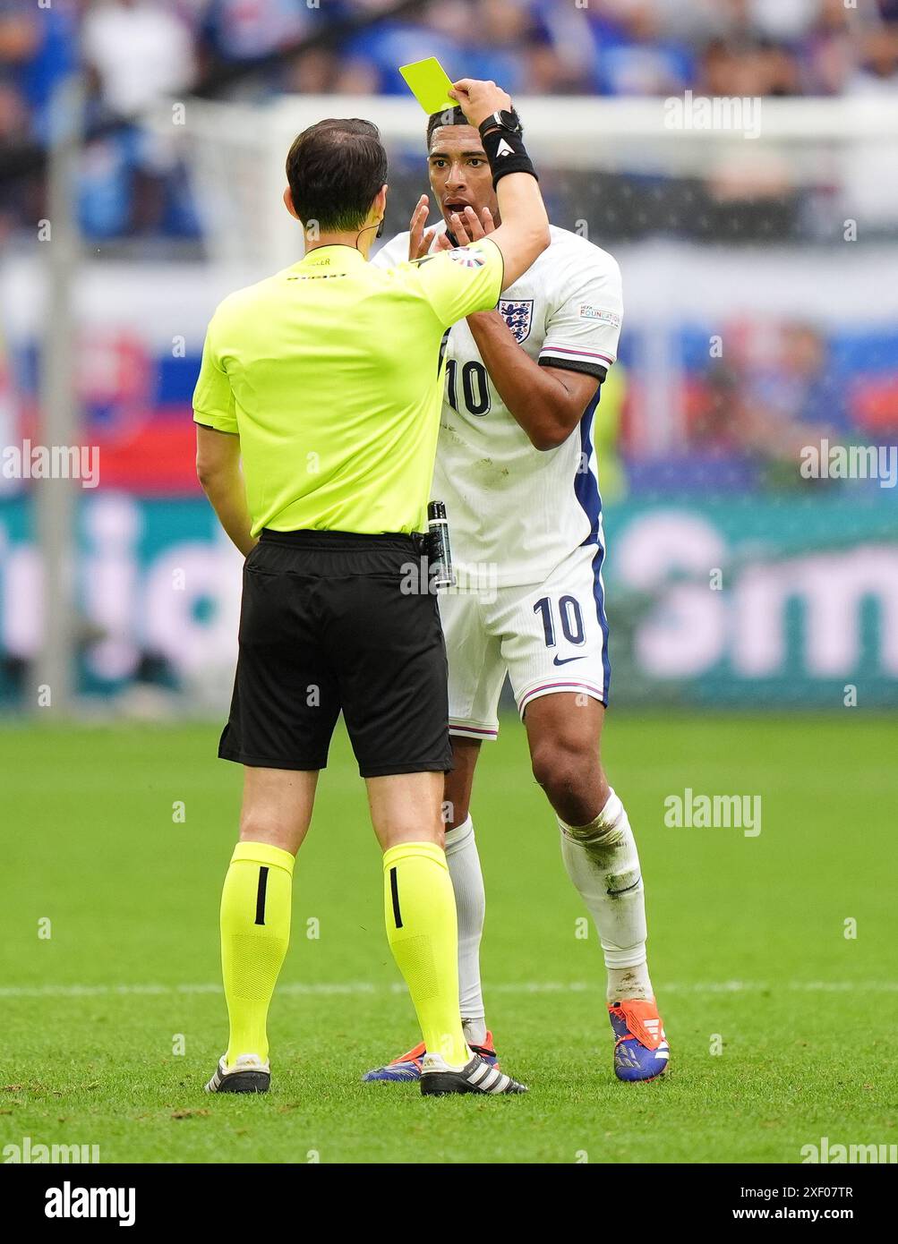 Der Englands Jude Bellingham reagiert darauf, als ihm während der UEFA Euro 2024 im Achtelfinale in der Arena AufSchalke in Gelsenkirchen eine gelbe Karte von Match Schiedsrichter Umut Meler (links) gezeigt wird. Bilddatum: Sonntag, 30. Juni 2024. Stockfoto