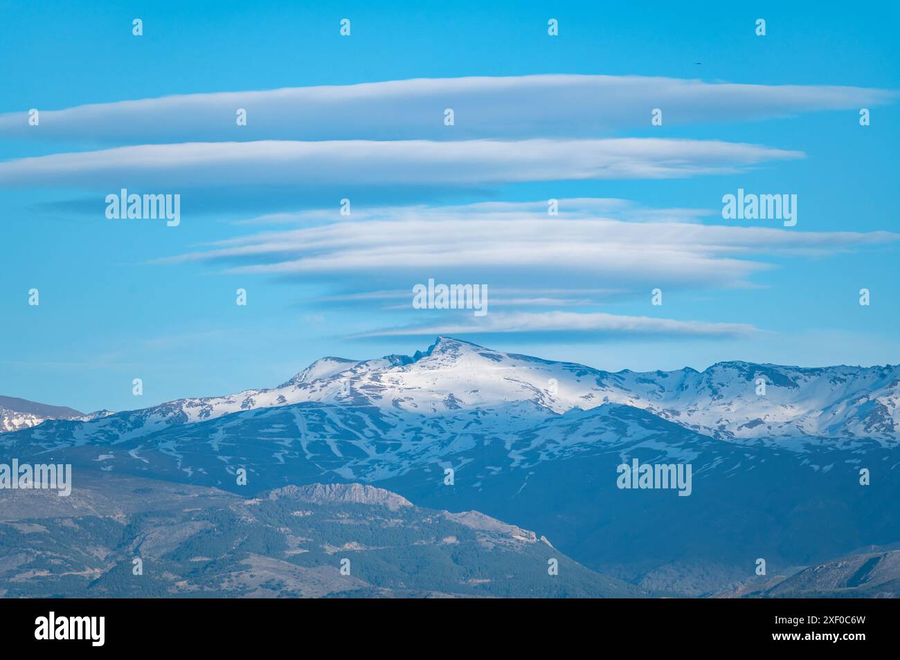 Riesige Lentikularwolken über den schneebedeckten Gipfeln der Sierra Nevada in Granada (Spanien) bei Sonnenuntergang Stockfoto