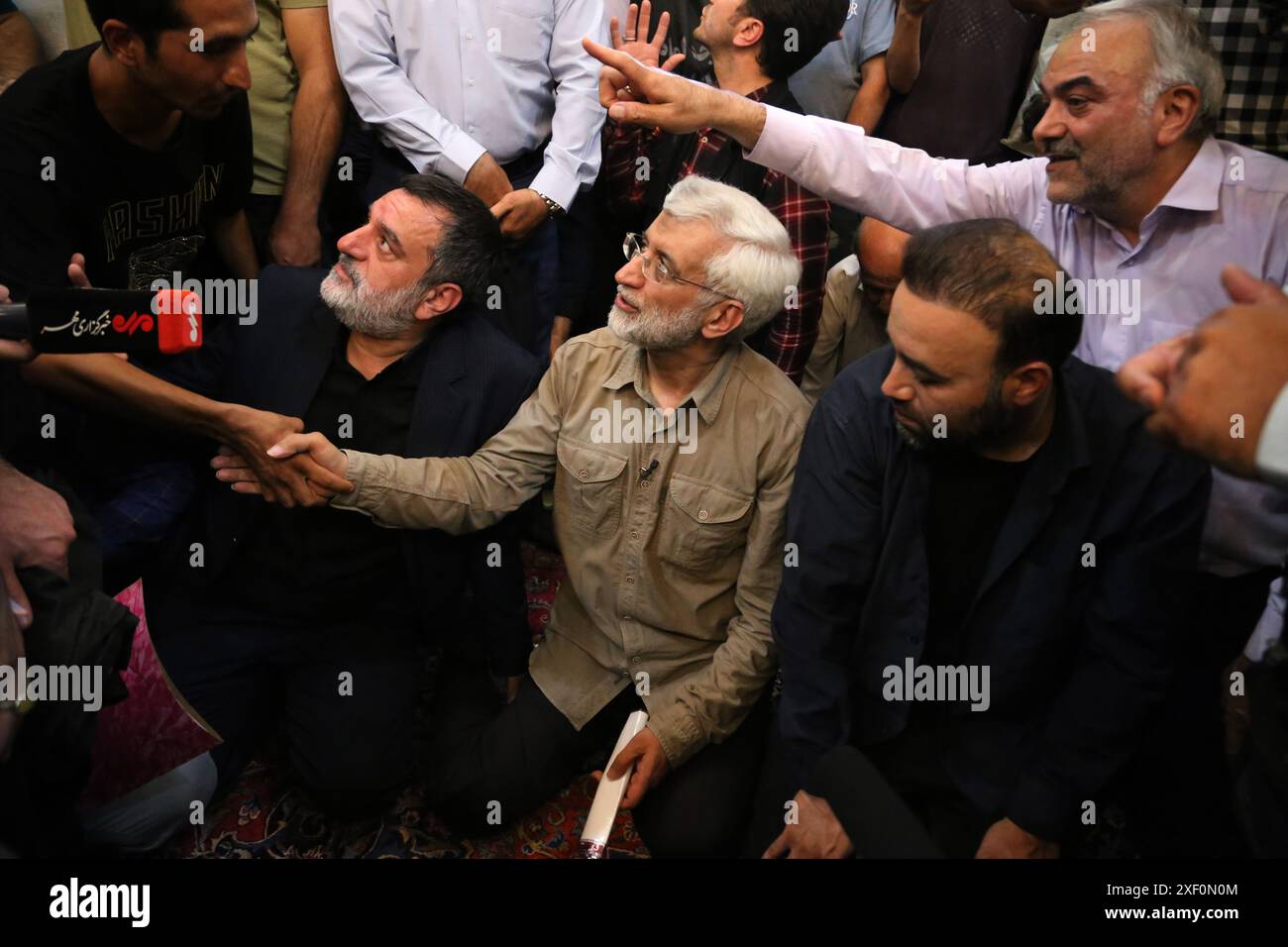 Teheran, Iran. 30. Juni 2024. Der iranische Präsidentschaftskandidat SAEED JALILI (C), ein ehemaliger iranischer Spitzenunterhändler im Nuklearbereich, schüttelt während eines Treffens mit einer Gruppe von Geschäftsleuten und Vermarktern im Rahmen seiner Wahlkampagne in der Imam-Moschee auf dem Großen Basar im Süden Teherans die Hand. Der konservative Jalili wird am 5. Juli gegen den Reformkandidaten Masoud Pezeshkian antreten, um den verstorbenen Hardline-Präsidenten Ebrahim Raisi zu ersetzen. Quelle: ZUMA Press, Inc./Alamy Live News Stockfoto