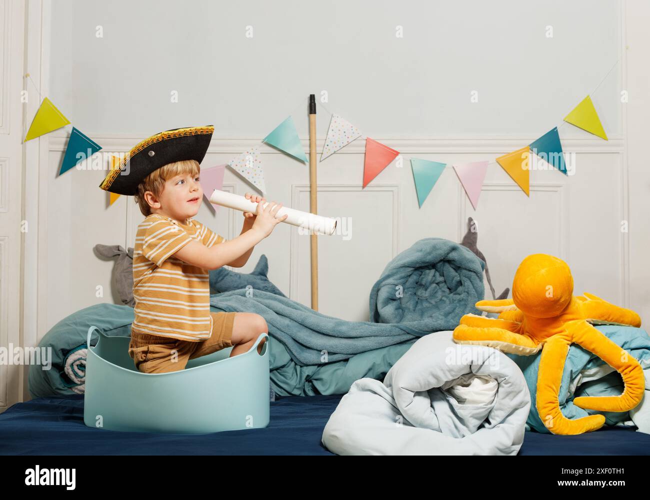 Ein Kind mit Piratenhut sieht durch ein provisorisches Teleskop Stockfoto