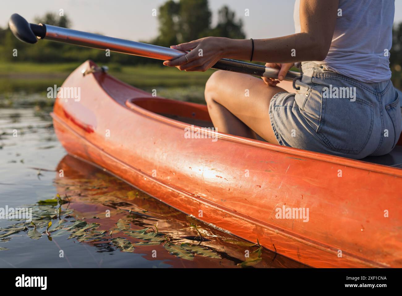 Entspannende Kanufahrt, eine Frau, die an einem angenehmen Sommertag auf dem malerischen See Kanu fährt. Naturliebhaber und aktive Lebenskonzepte. Stockfoto