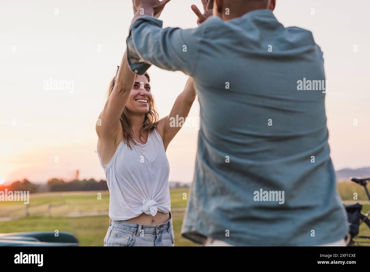 Glückliches junges Paar bei einer Kanufahrt, die High 5 auf einem wunderschönen grünen See gibt Stockfoto